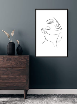 Minimalist line art poster of a woman's face with beautiful lips, framed and hung on a modern wall.