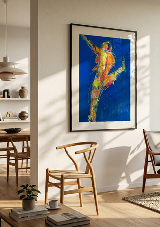 Blue Dancer by René J in a black frame in a bright dining room with wooden chairs