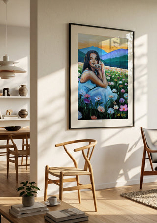 Where Wildflowers Dream by Nella Hajdu in a black frame in a bright dining room with wooden chairs