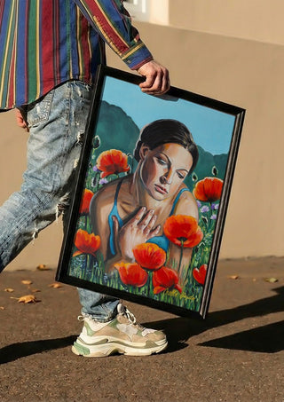 A Moment of Stillness by Nella Hajdu carried in a black frame along a sunny street