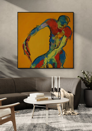 Bending Figure by René J in a black frame above a grey sofa with a round coffee table and candlesticks