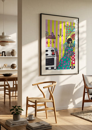 Afternoon with the Cat by Camilla Nilsson in a black frame in a bright dining room with wooden chairs