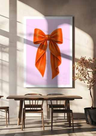 Orange velvet bow on pink by Ohkimiko hanging above a wooden dining table in warm sunlight
