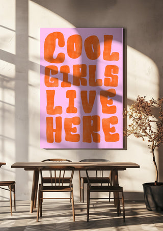 Cool girls live here by Ohkimiko hanging above a wooden dining table in warm sunlight