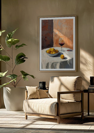 Summer scene: Lemons and wine by Ohkimiko framed above a beige armchair beside a potted plant