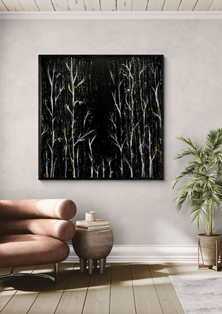 White Birches at Night by Marcel Herrmann in a black frame above a leather armchair beside a palm
