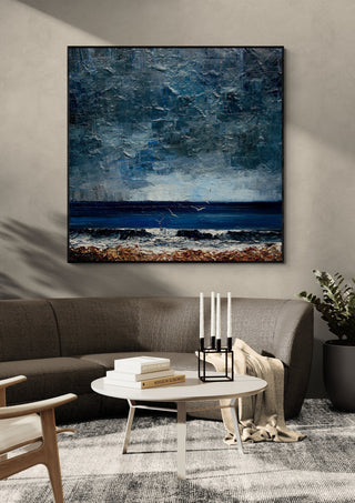 Surf under a Grey Sky by Justyna Kopania in a black frame above a dark sofa with candlesticks on a round table