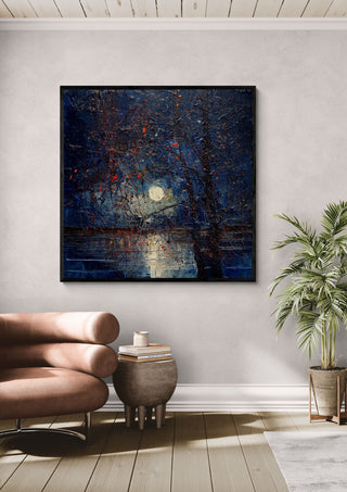 Moon through Bare Trees by Justyna Kopania in a black frame above a leather armchair beside a palm