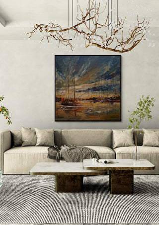 Masts in Golden Light by Justyna Kopania in a black frame above a cream sofa under a branch chandelier