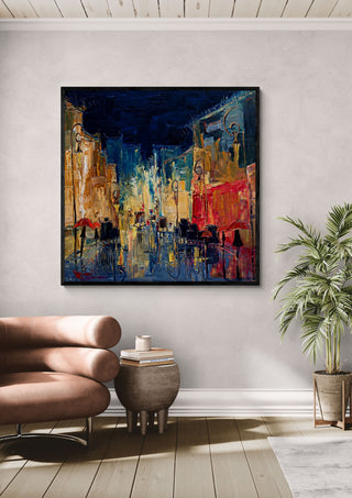 Night Street with Red Umbrellas by Justyna Kopania in a black frame above a leather armchair beside a palm