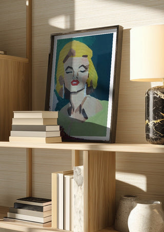 Marilyn Monroe by creatievananne in a dark frame on a wooden shelf beside books and a lamp