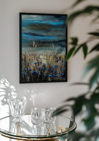 Blue fields by Lüba in a black frame above a glass table with crystal glassware