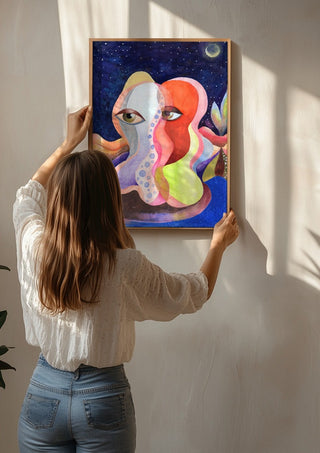 Two Faces Under the Moon by Shimmering Ugly being hung on a sunlit wall