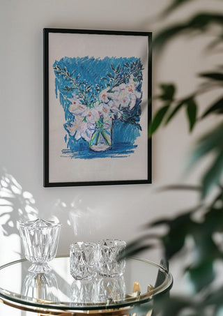 White Blooms on Blue by DNF in a black frame above a glass table with crystal glassware