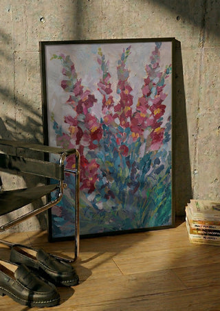 Red Snapdragon Flowers by DNF in a black frame leaning against a concrete wall by a steel chair