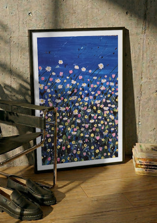 Daisies by Rebecca Wright in a black frame leaning against a concrete wall by a steel chair