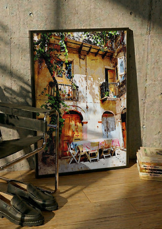 Italian courtyard by Massimo Frascogna in a black frame leaning against a concrete wall by a steel chair