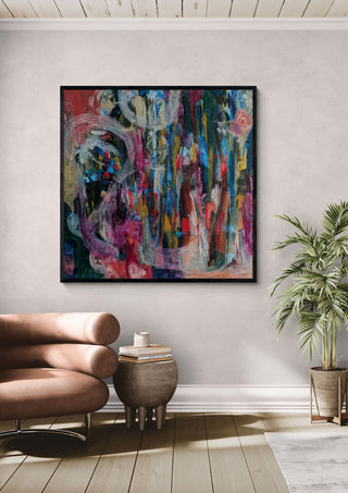 All Roads Lead Home by Janet Bell in a black frame above a tan leather sofa beside a potted palm
