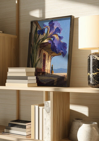 The Station in Bloom by Matthews Gallerie in a dark frame on a wooden shelf beside books and a lamp