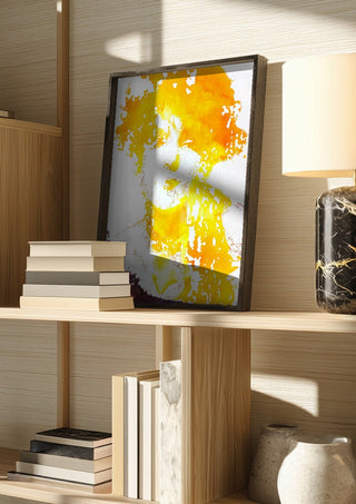 Sunshine by Bent Hardervig in a dark frame on a wooden shelf beside books and a lamp