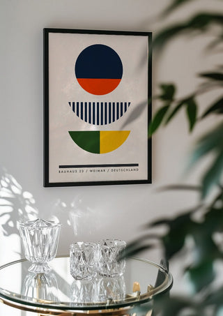 Bauhaus Circles by Neil Stevens in a black frame above a glass table with crystal glassware
