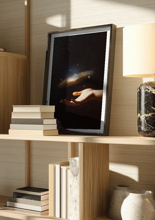 Supernova by Fran Rodriguez in a dark frame on a wooden shelf beside books and a lamp