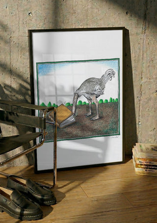 The Ostrich and the Book by Waldemar Mandzel in a black frame leaning against a concrete wall by a steel chair