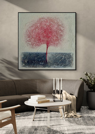 Red Tree by Marina Agre in a black frame above a dark grey sofa with a round table and candlesticks