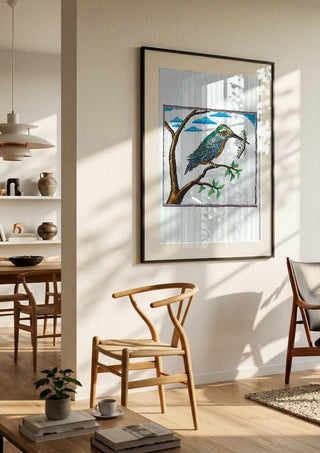 Bird with a Book by Waldemar Mandzel in a black frame in a bright dining room with wooden chairs