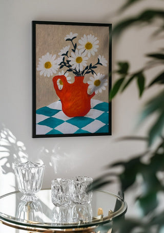 Vita blomster i röd vas by Rebecka Hansson in a black frame above a glass table with crystal glassware