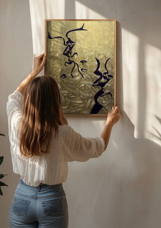 Whispers in Gold by Bibi being hung on a sunlit wall