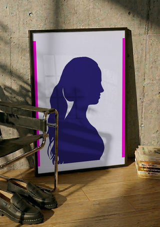 Femininity by Tonia in a black frame leaning against a concrete wall by a steel chair