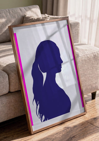 Femininity by Tonia in a walnut frame leaning against a grey sofa