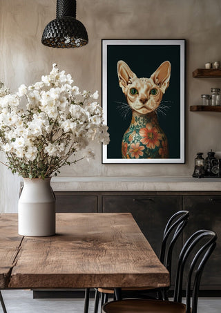 Tattooed Sphynx by Nari in a black frame above a rustic table with white flowers