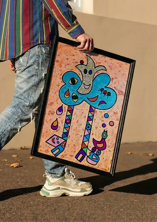 Blue Tree with Faces by Steffi Seiler carried in a black frame along a sunny street