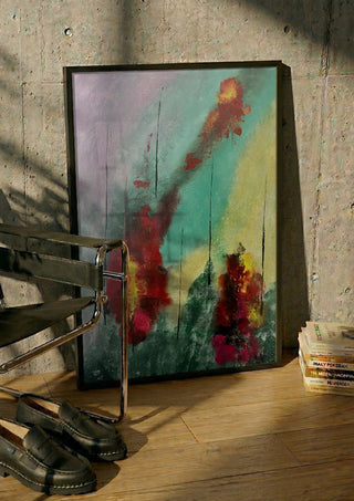 Smoke and Ember by Miguel Lemos in a black frame leaning against a concrete wall by a steel chair