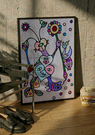 Hearts and Sunflower by Steffi Seiler in a black frame leaning against a concrete wall by a steel chair