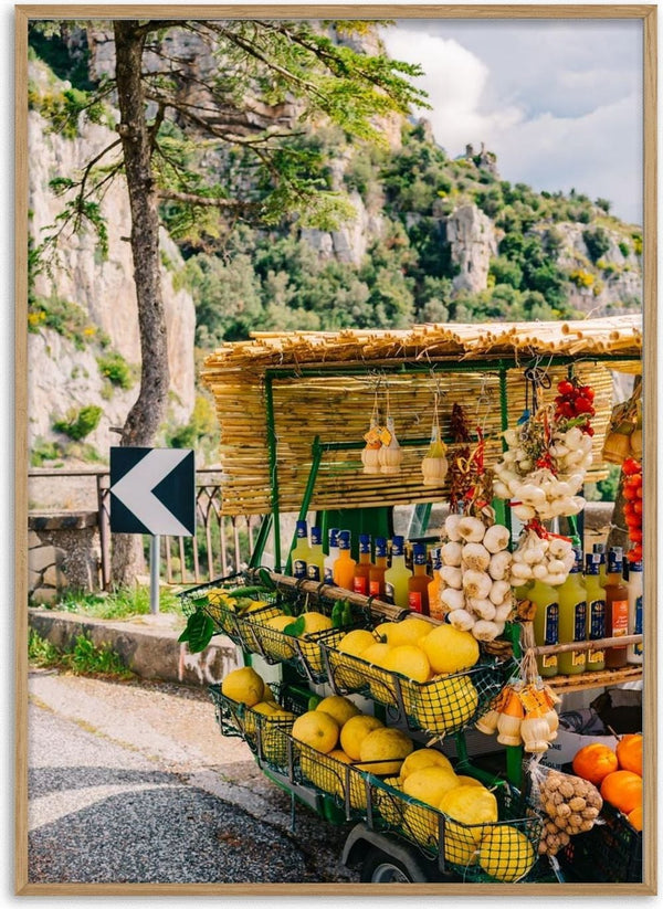 Street-side stall with lemons, garlic, and beverages on Amalfi Coast Drive with scenic cliffs in the background.