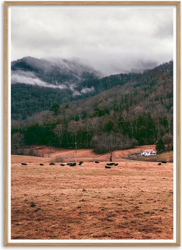 Poster showing misty mountains, a forest, grazing cows, and a small farmhouse in an open field.